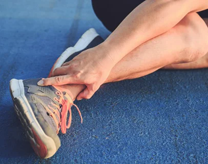 Sports Injuries runner lying down on track holding injured ankle therapy first salford media city uk